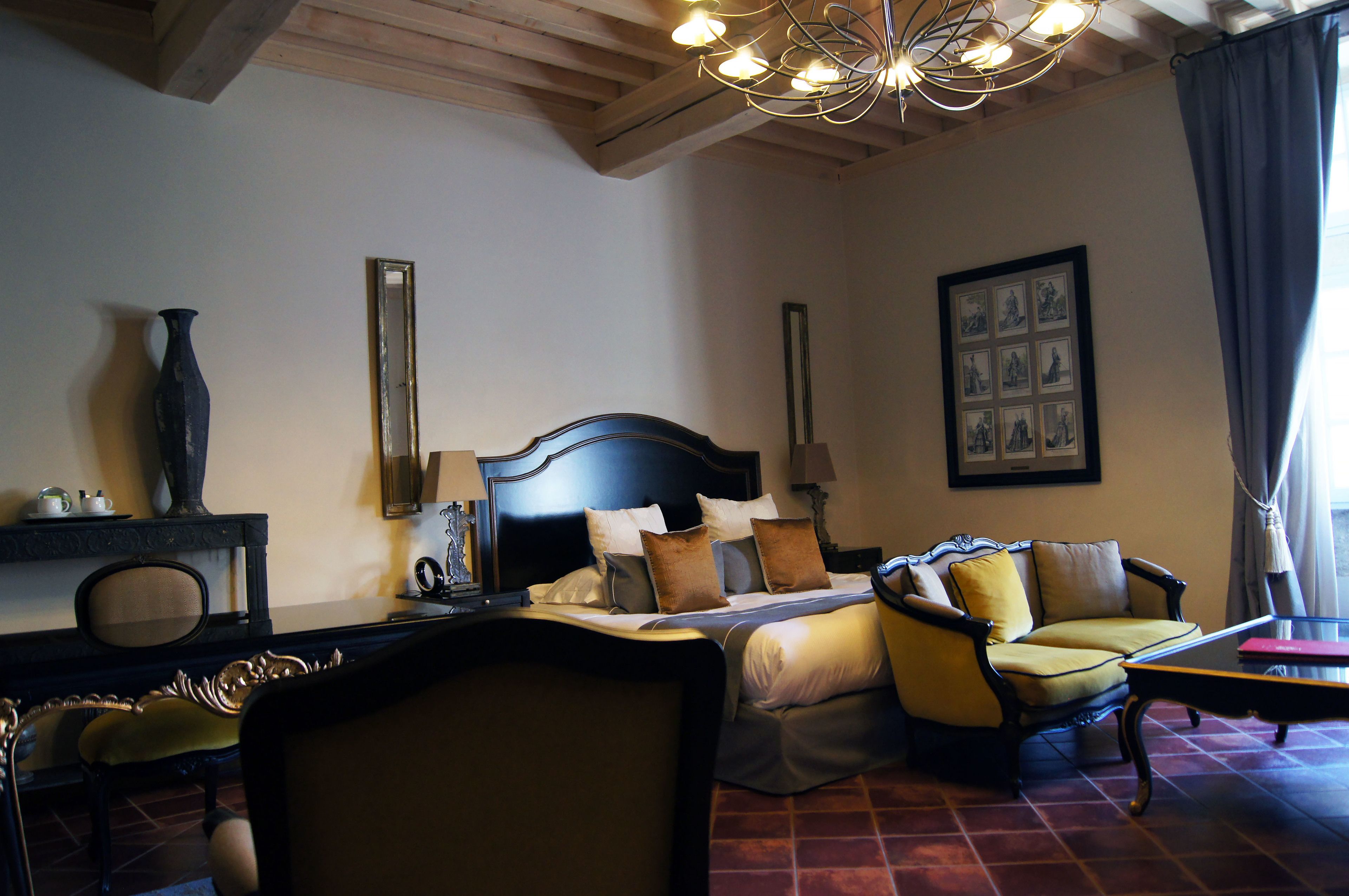 Habitación de hotel con una cama grande, un sofá, un escritorio y una araña.
