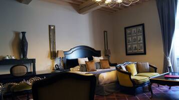 Habitación de hotel con una cama grande, un sofá, un escritorio y una araña.
