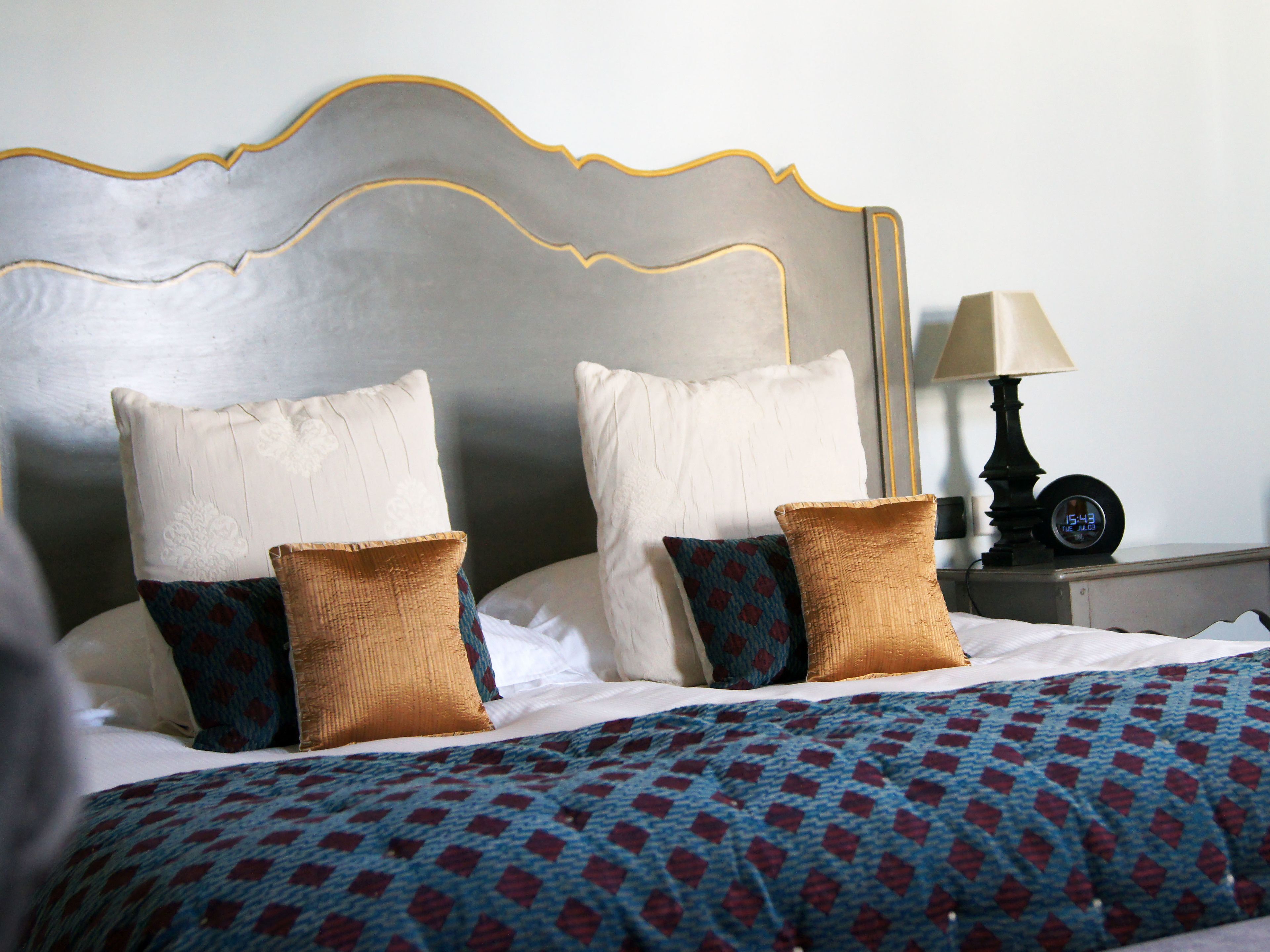 A neatly made bed with a patterned bedspread, two white pillows, and two decorative pillows.
