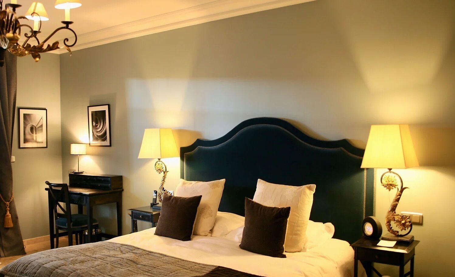 A hotel room with a bed, two bedside tables with lamps, a desk, and a chair.