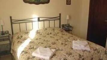 A bedroom with a single bed, a nightstand, a lamp, and a painting on the wall.