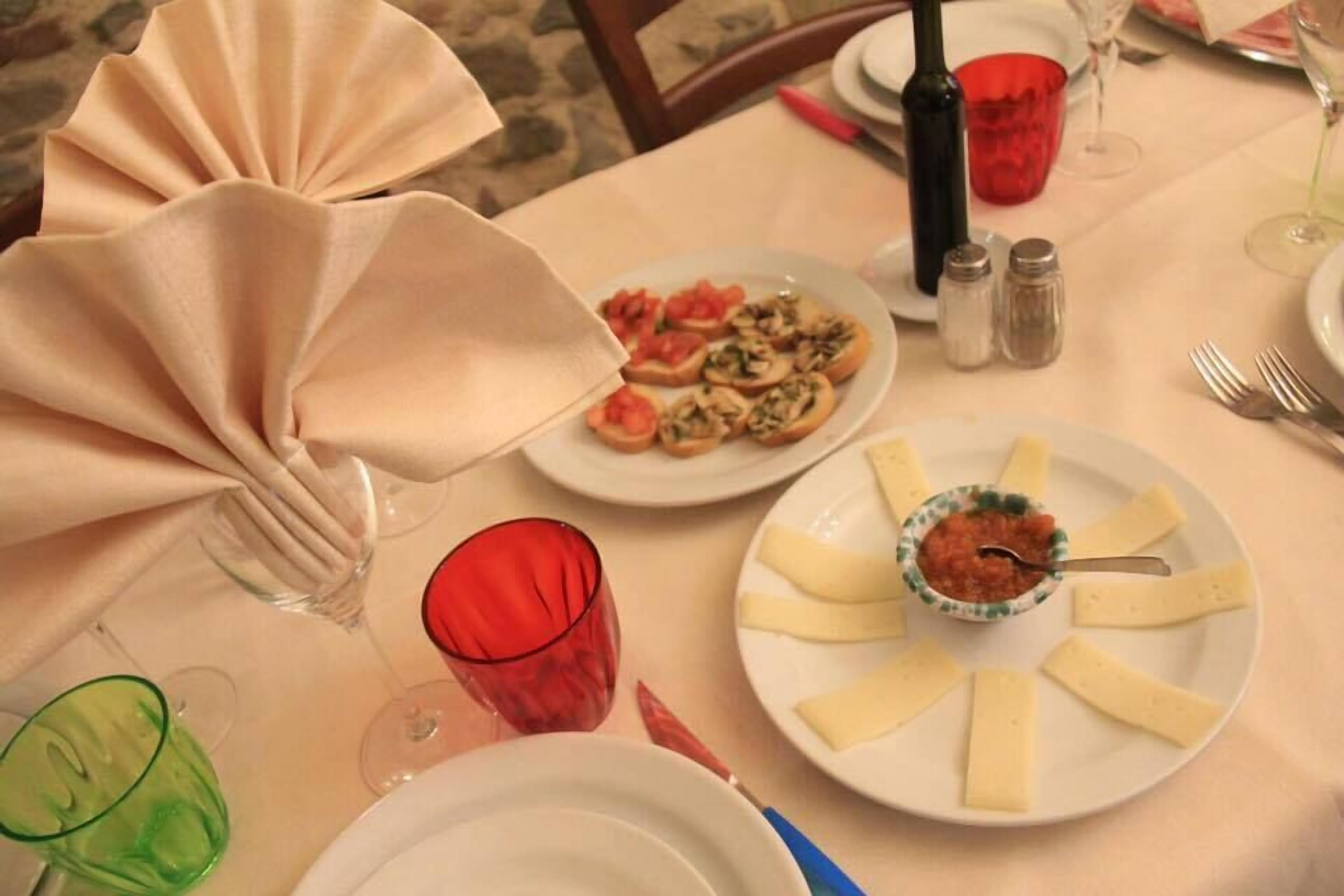 A table set for a meal with plates of food, glasses, and a bottle.