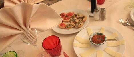 Una mesa servida para una comida, con platos de comida, vasos y una botella.
