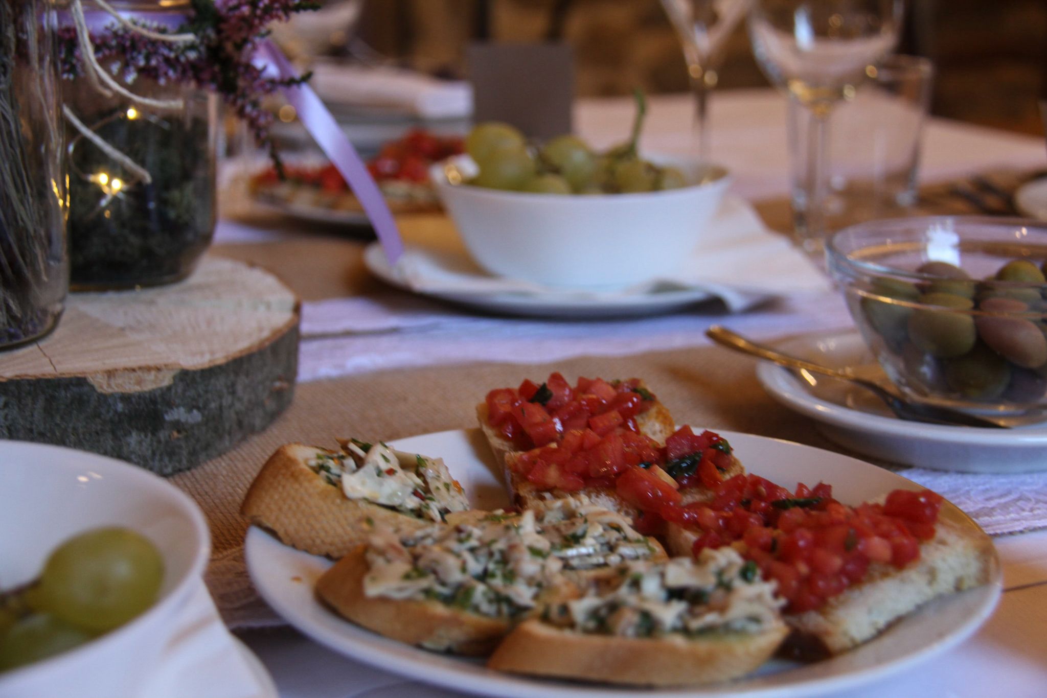 Un tavolo da pranzo con piatti di cibo, tra cui pizza e una ciotola di olive.