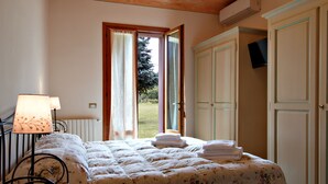 Een slaapkamer met een bed, nachtkastje, lamp en uitzicht op de omgeving.