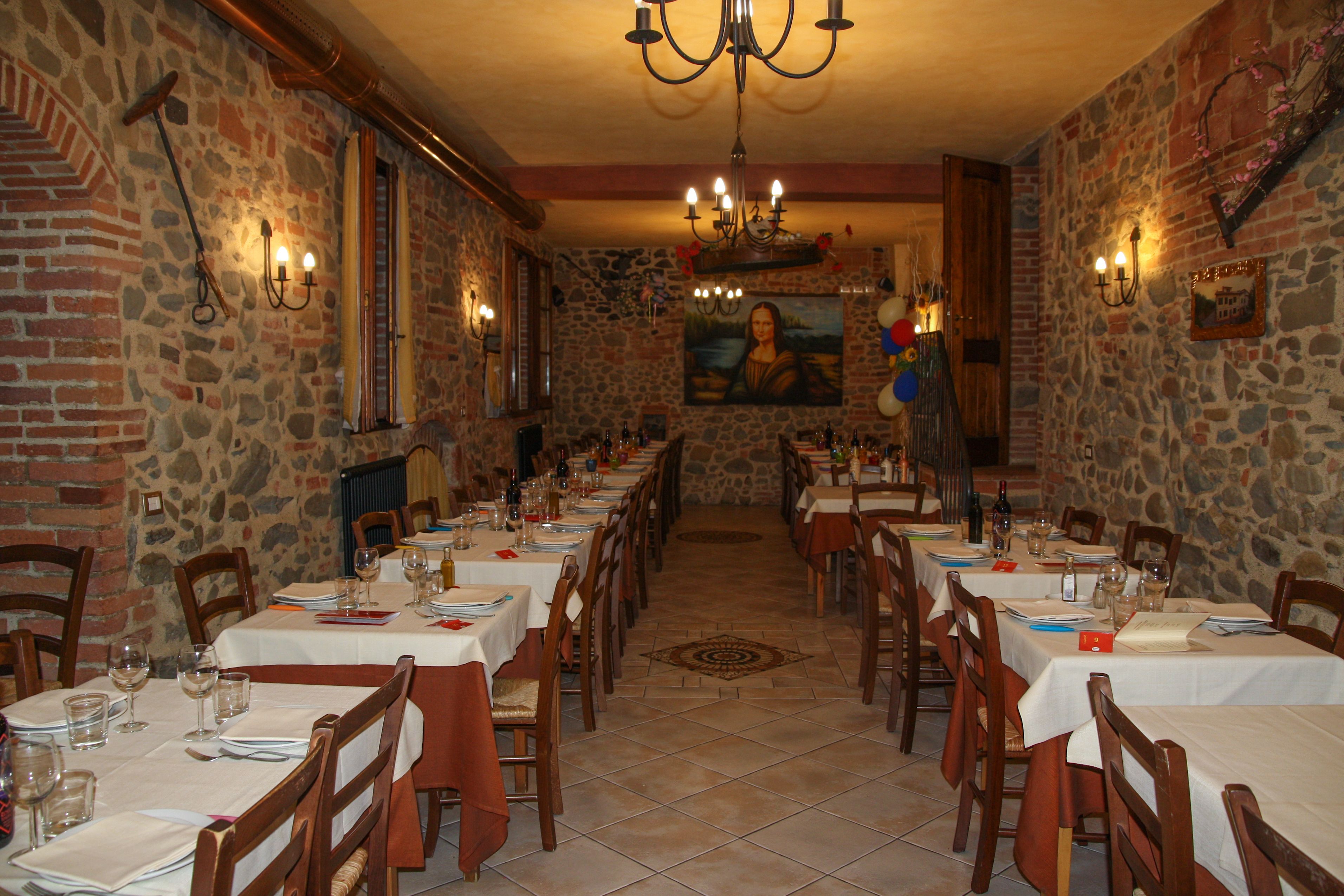 A restaurant with stone walls, wooden tables, and a chandelier.