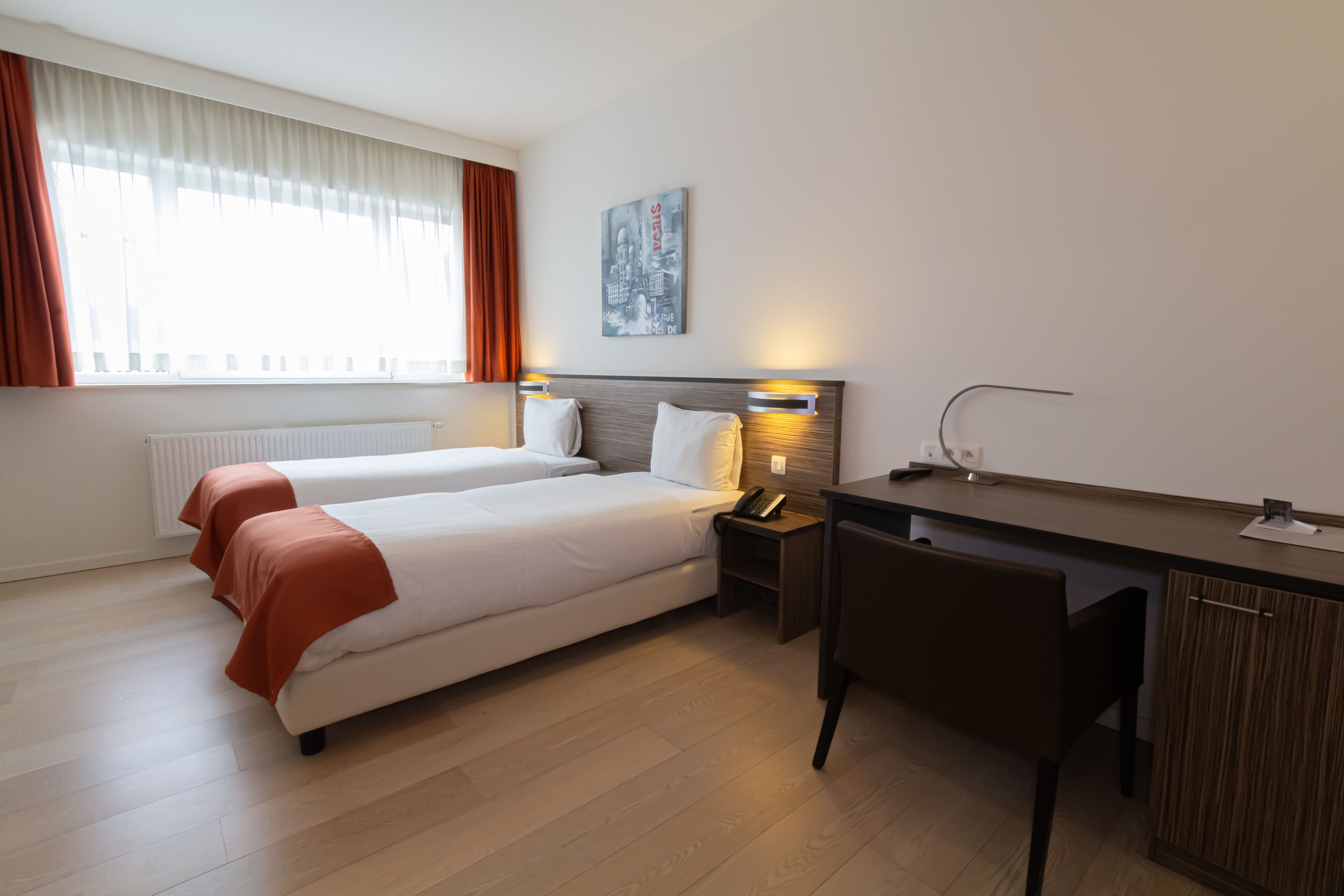 A hotel room with two beds, a desk, and a chair.