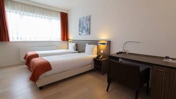 A hotel room with two beds, a desk, and a chair.