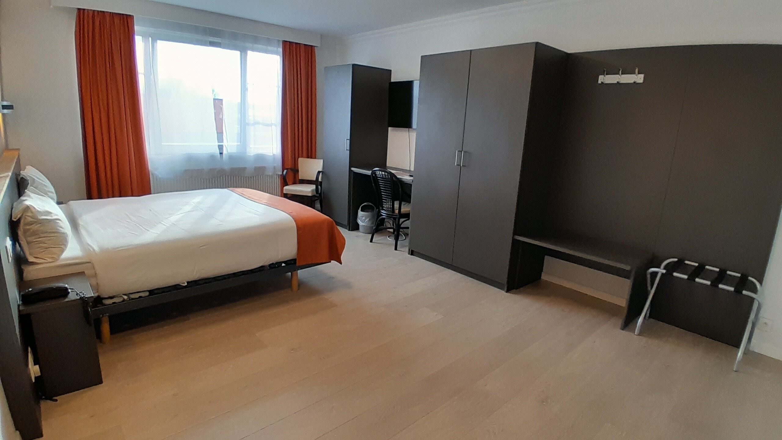 Een hotelkamer met een bed, een bureau, een stoel en een kledingkast.