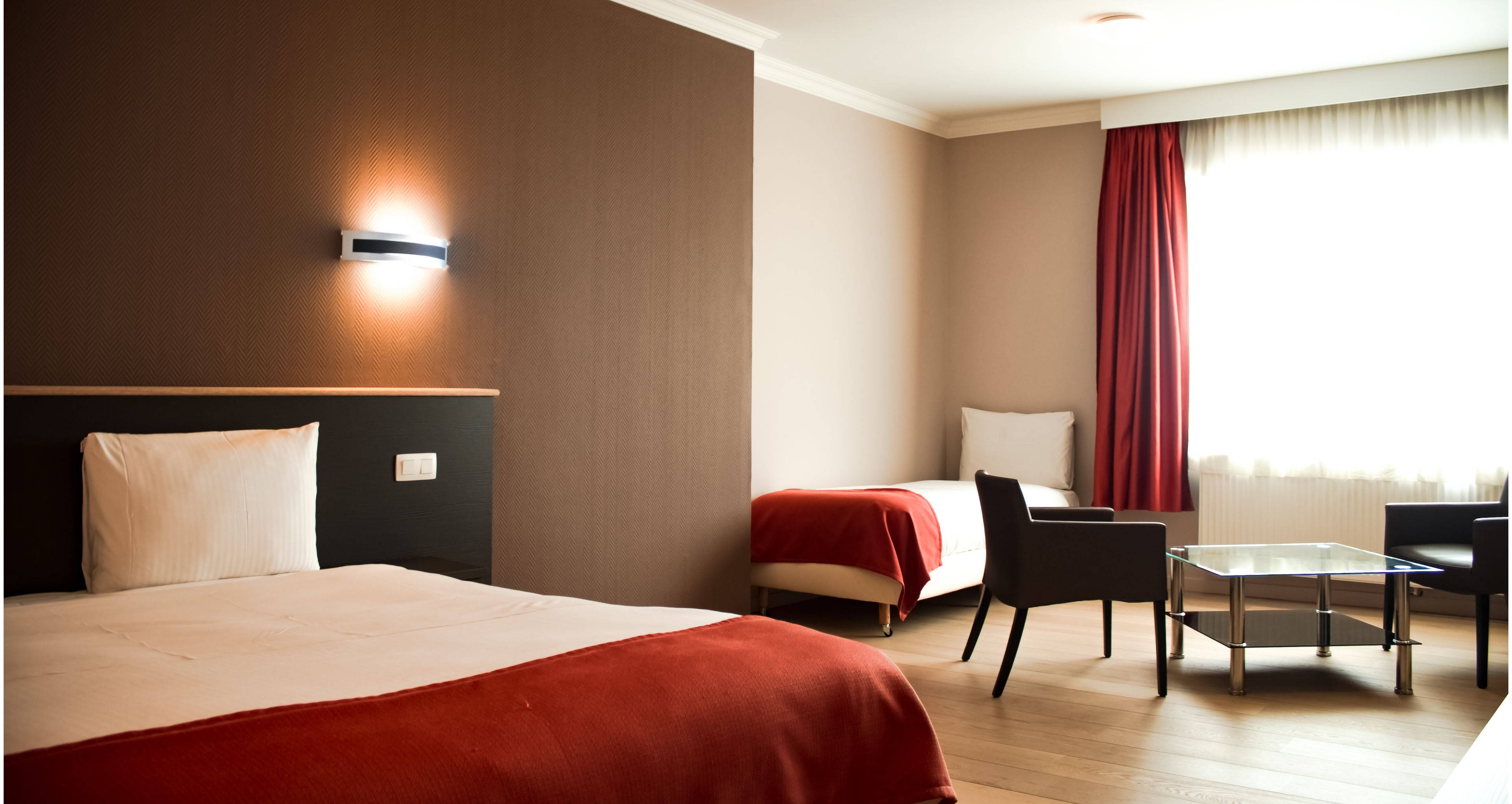 A hotel room with a large bed, a desk, a chair, and a window with curtains.