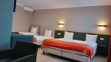 A hotel room with two beds, a desk, and a chair.