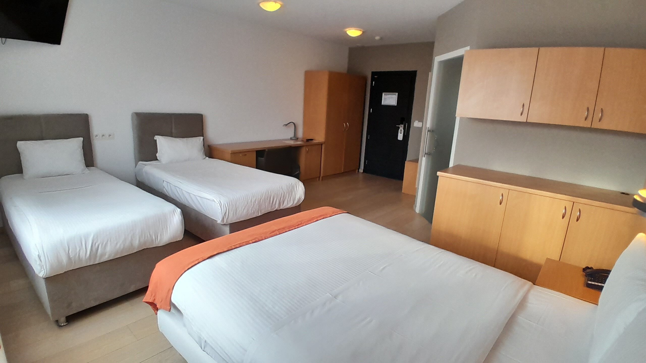 Una camera d'albergo con due letti singoli, una scrivania, un armadio e un bagno.
