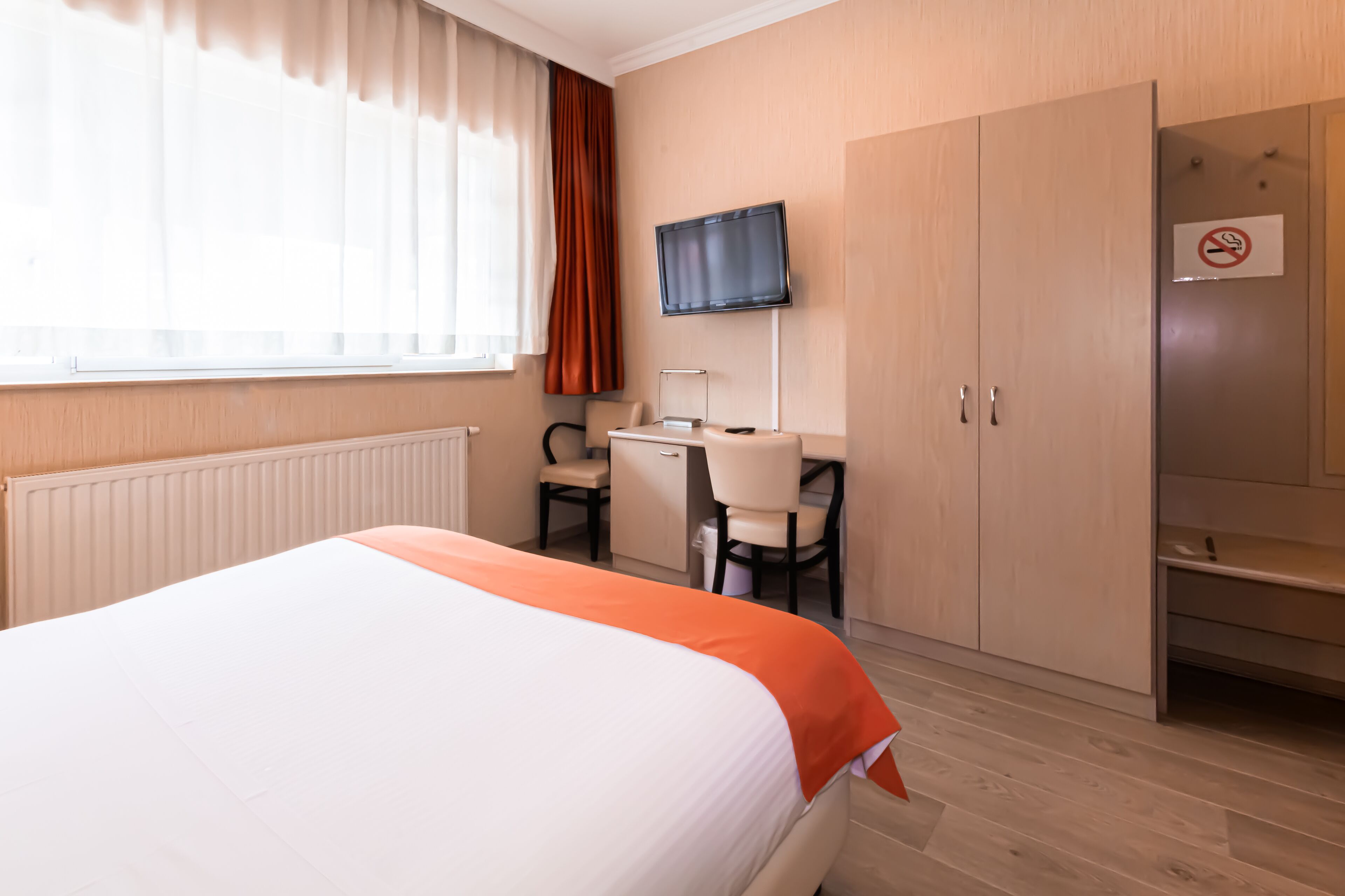 Une chambre d’hôtel équipée d’un lit, d’un bureau, d’une chaise, d’une télévision et d’une armoire.