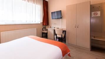 Une chambre d’hôtel équipée d’un lit, d’un bureau, d’une chaise, d’une télévision et d’une armoire.