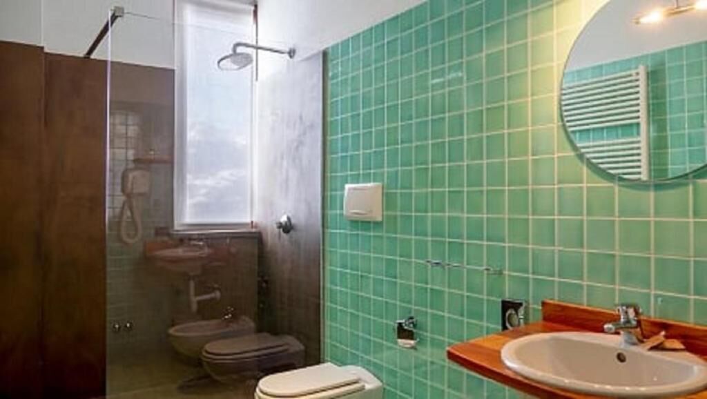 Un baño con ducha, inodoro, lavamanos y espejo.