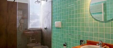 Un baño con ducha, inodoro, lavamanos y espejo.