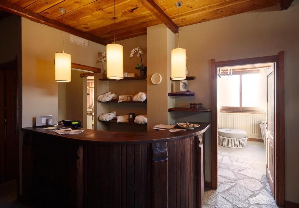 A reception area with a wooden counter, hanging pendant lights, a clock, and a view of the outside.