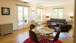A living room with a glass table, leather chairs, a sofa, and a red rug. - Hotel de Charme L'Amandière (St.-Rémy-de-Provence)