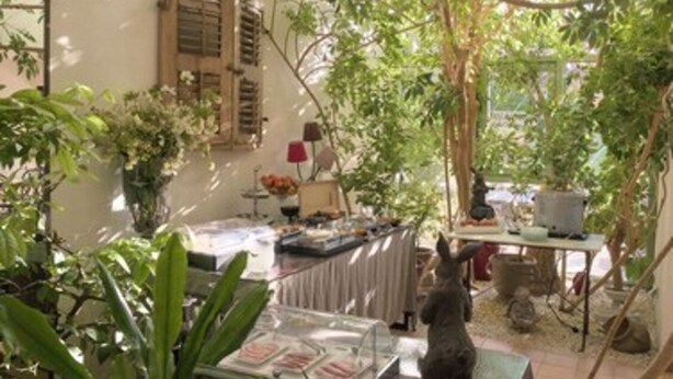 An indoor garden area with a dining table, chairs, and a statue. - Hotel de Charme L'Amandière (St.-Rémy-de-Provence)