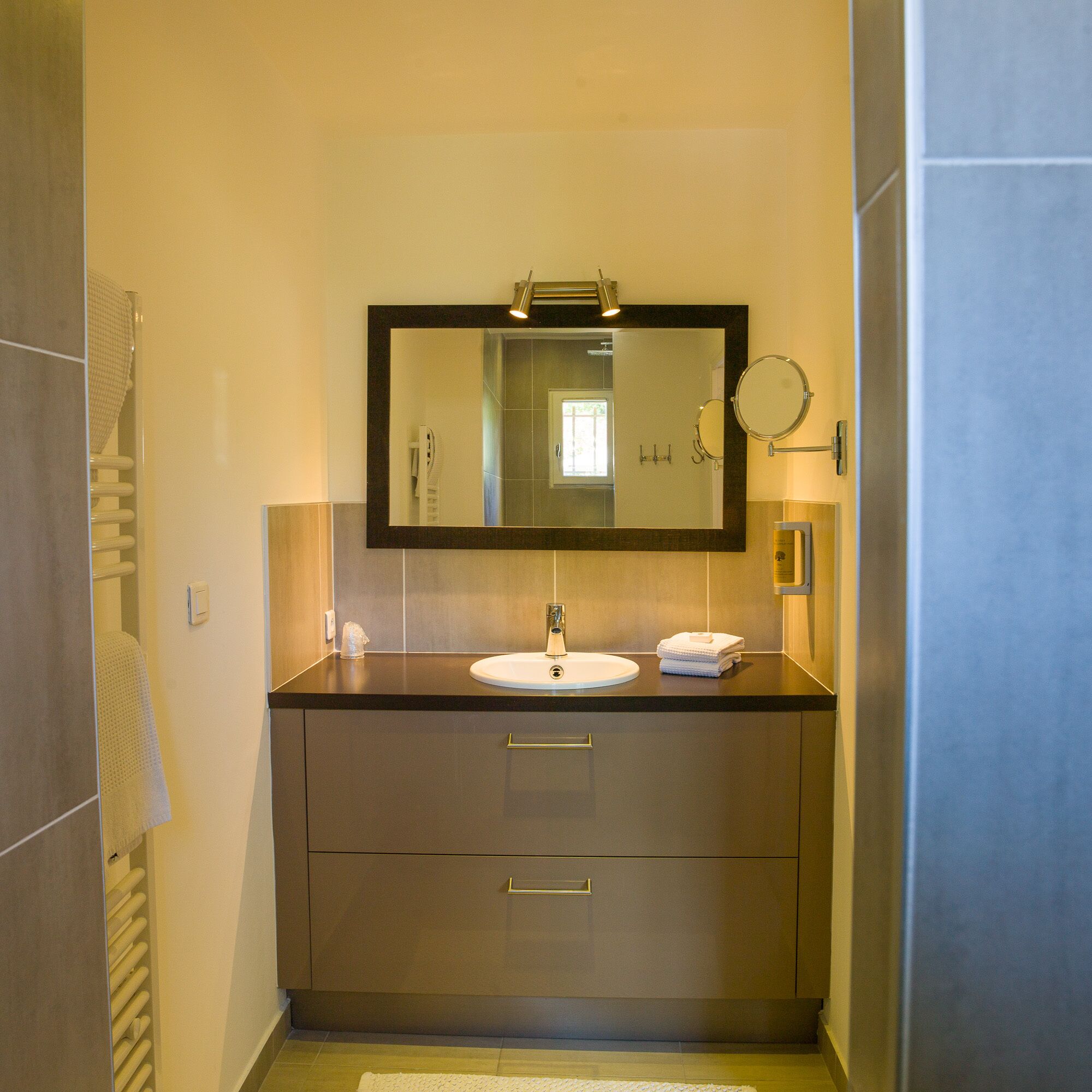 A modern bathroom with a large mirror, a sink, and a towel rack.