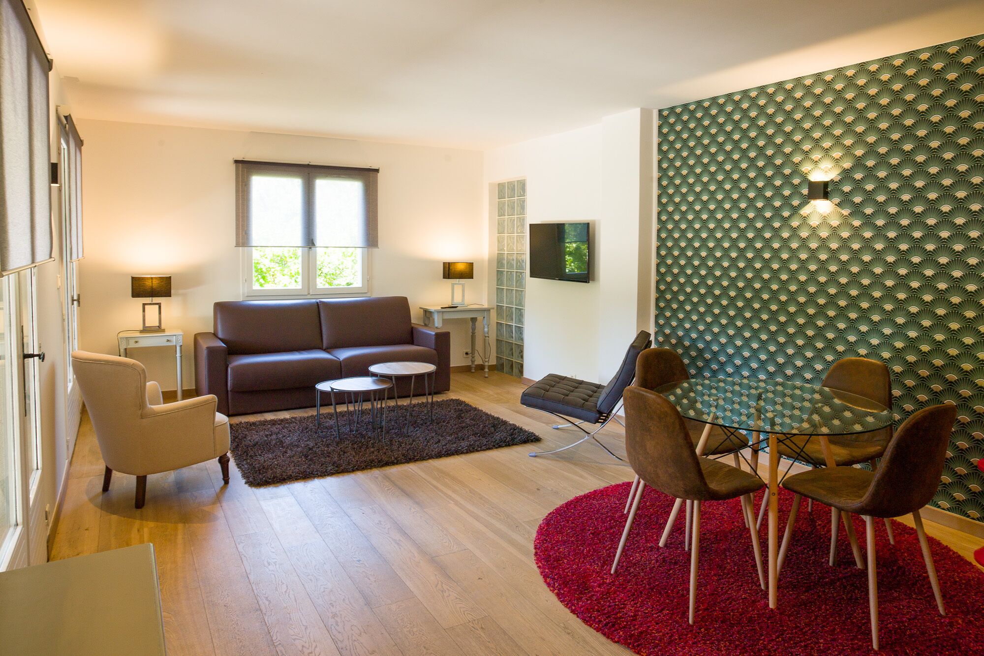 Una sala de estar moderna con un sofá, sillas, un televisor y una pared decorada.