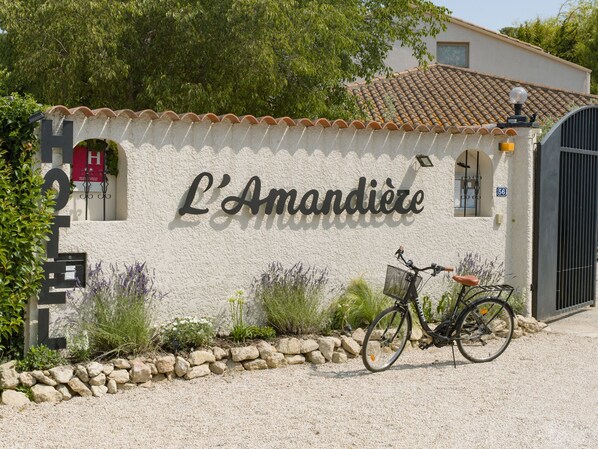 A building with a sign reading "L'Amandier" and a bicycle parked in front. - Hotel de Charme L'Amandière (St.-Rémy-de-Provence)