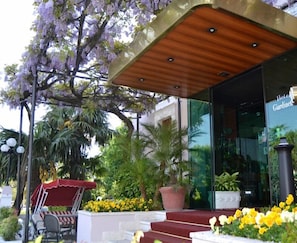 A hotel entrance with a wooden canopy, outdoor seating, and a variety of plants and flowers. - Giardinetto (Desenzano del Garda)