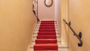 Una escalera con peldaños cubiertos de alfombra roja y barandilla de metal.