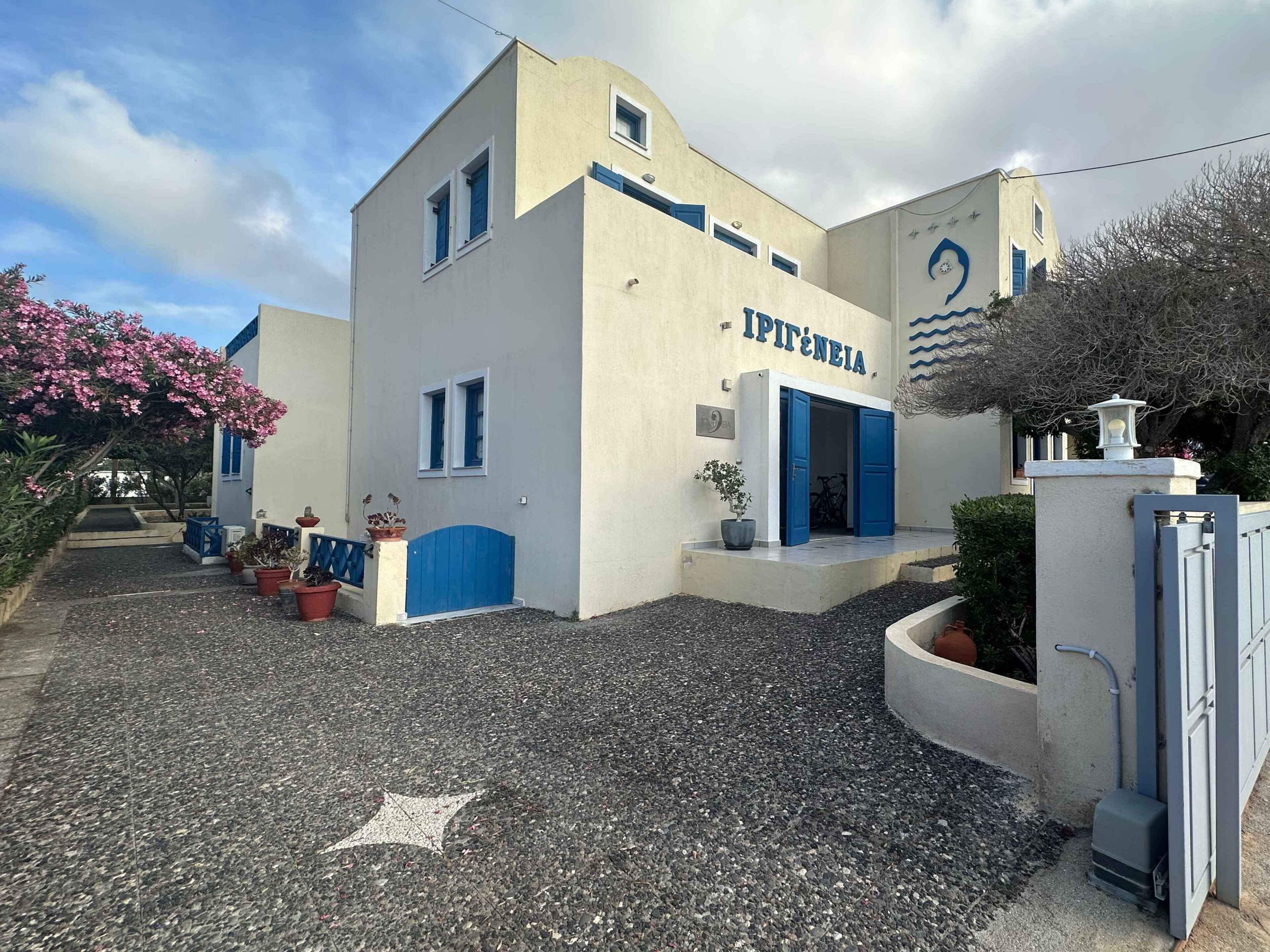 A building with a sign reading 'IPITÊNEIA,' a gravel driveway, and potted plants.