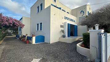 A building with a sign reading 'IPITÊNEIA,' a gravel driveway, and potted plants.