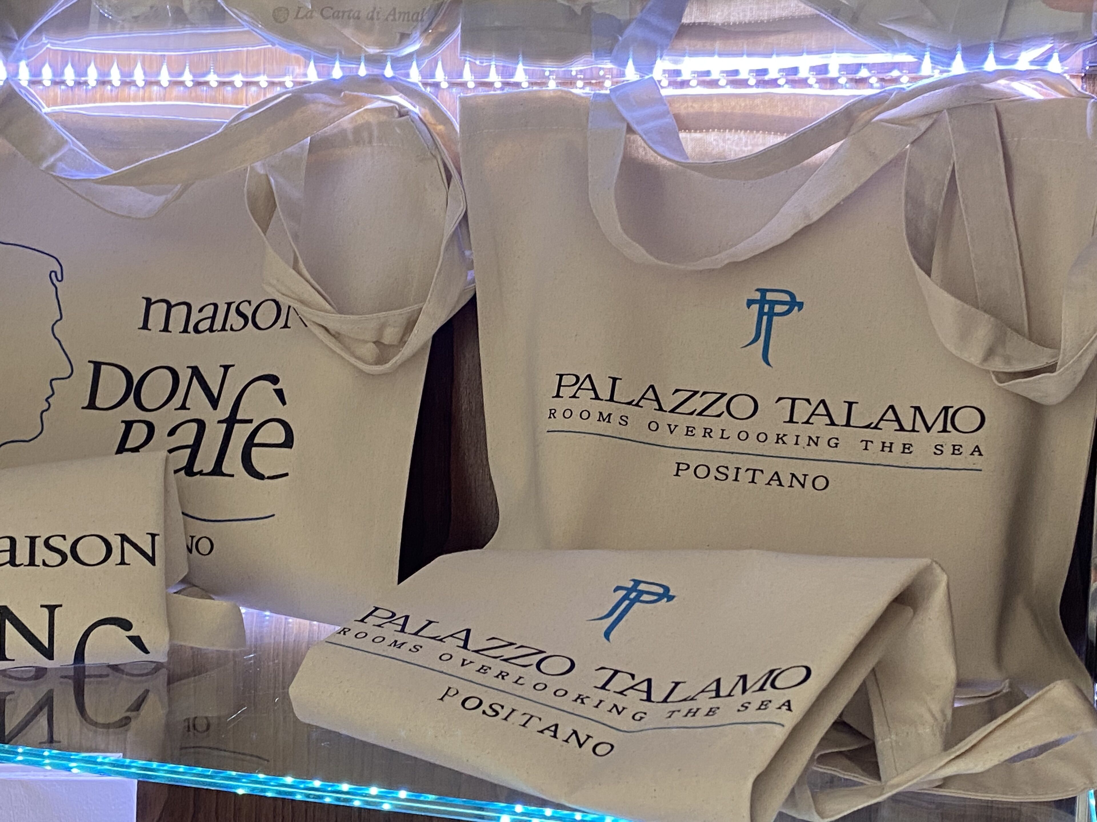 A display of bags with the text "Palazzo Talamo" and "Rooms overlooking the sea" indicating the hotel name and a feature of the rooms.