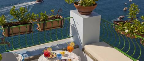 A balcony with a table set for dining, overlooking a body of water with boats.