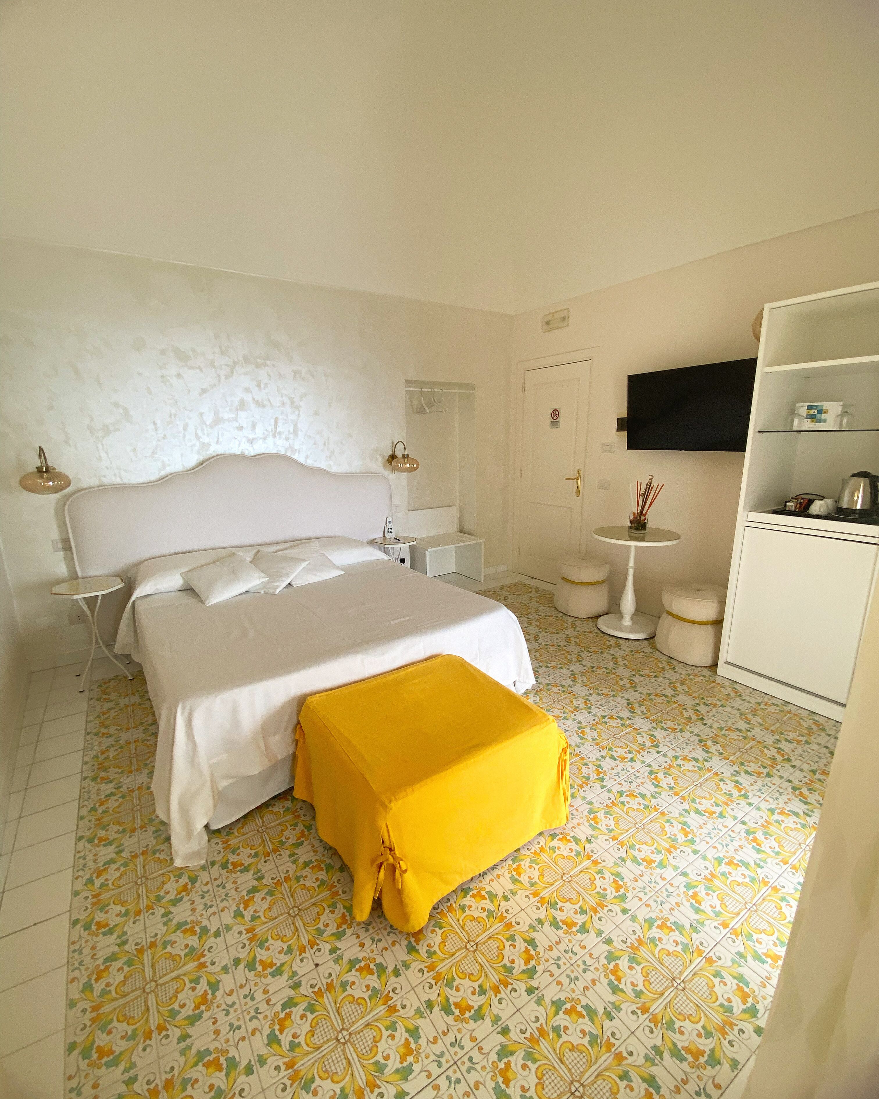 A bedroom with a bed, bedside tables, a small round table, a TV, and a wardrobe.
