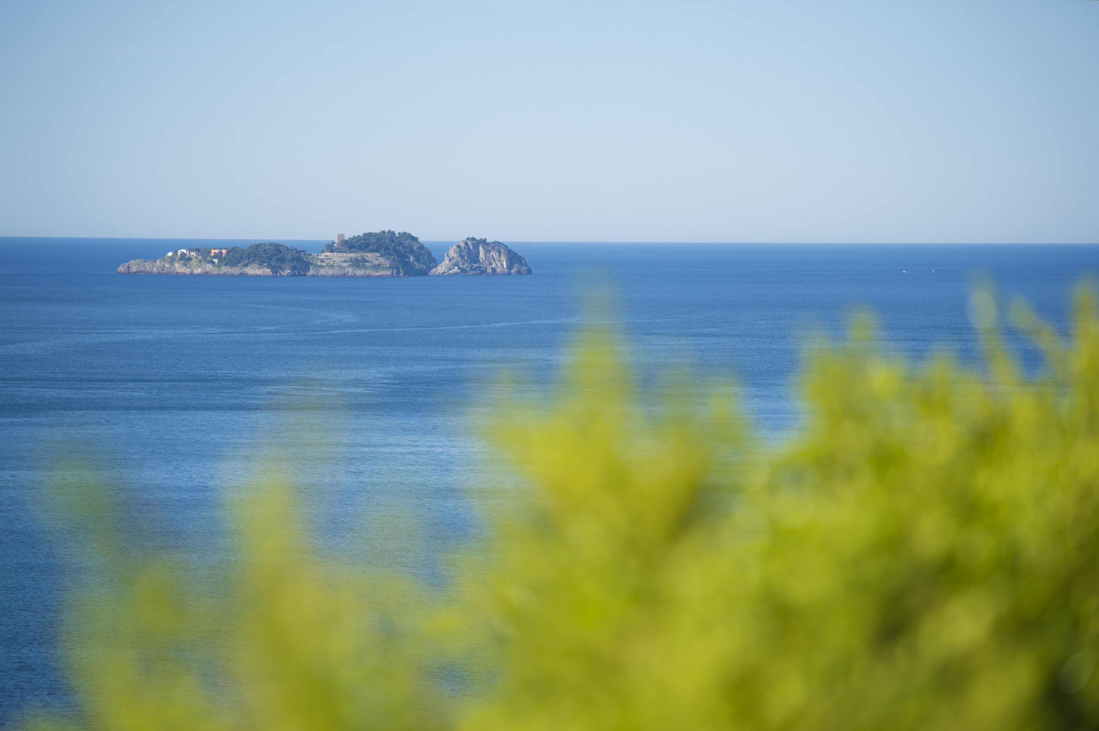 Un paisaje costero con una pequeña isla y mar tranquilo.