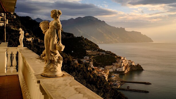 A statue on a balcony overlooking a coastal town with mountains in the background. - Holiday House Le Palme (Amalfi)