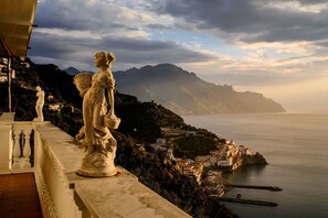 A statue on a balcony overlooking a coastal town with mountains in the background. - Holiday House Le Palme (Amalfi)