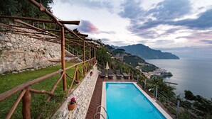 A pool with a stone wall and wooden pergola, overlooking a coastal town and sea. - Holiday House Le Palme (Amalfi)