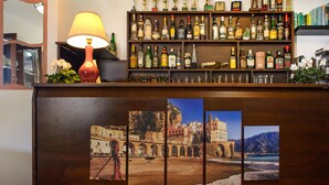A bar area with a variety of liquor bottles, a lamp, and framed pictures of coastal scenes. - Holiday House Le Palme (Amalfi)
