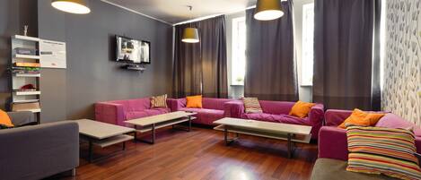 A modern living room with a sofa set, two tables, and a television.