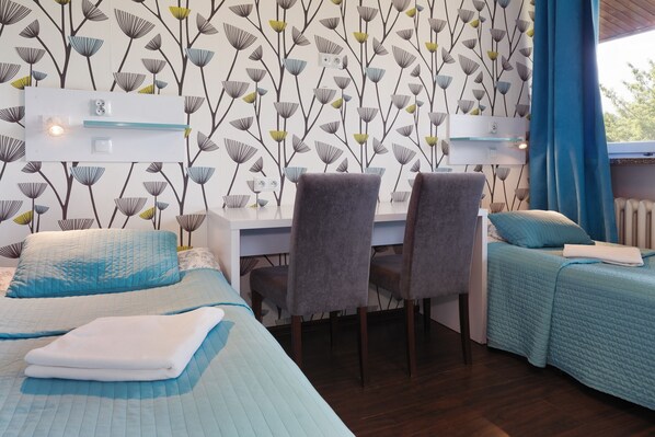 A bedroom with two beds, a desk, and chairs. - Tatamka Hostel (Warsaw)