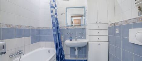 A bathroom with a bathtub, a sink, and a cabinet.