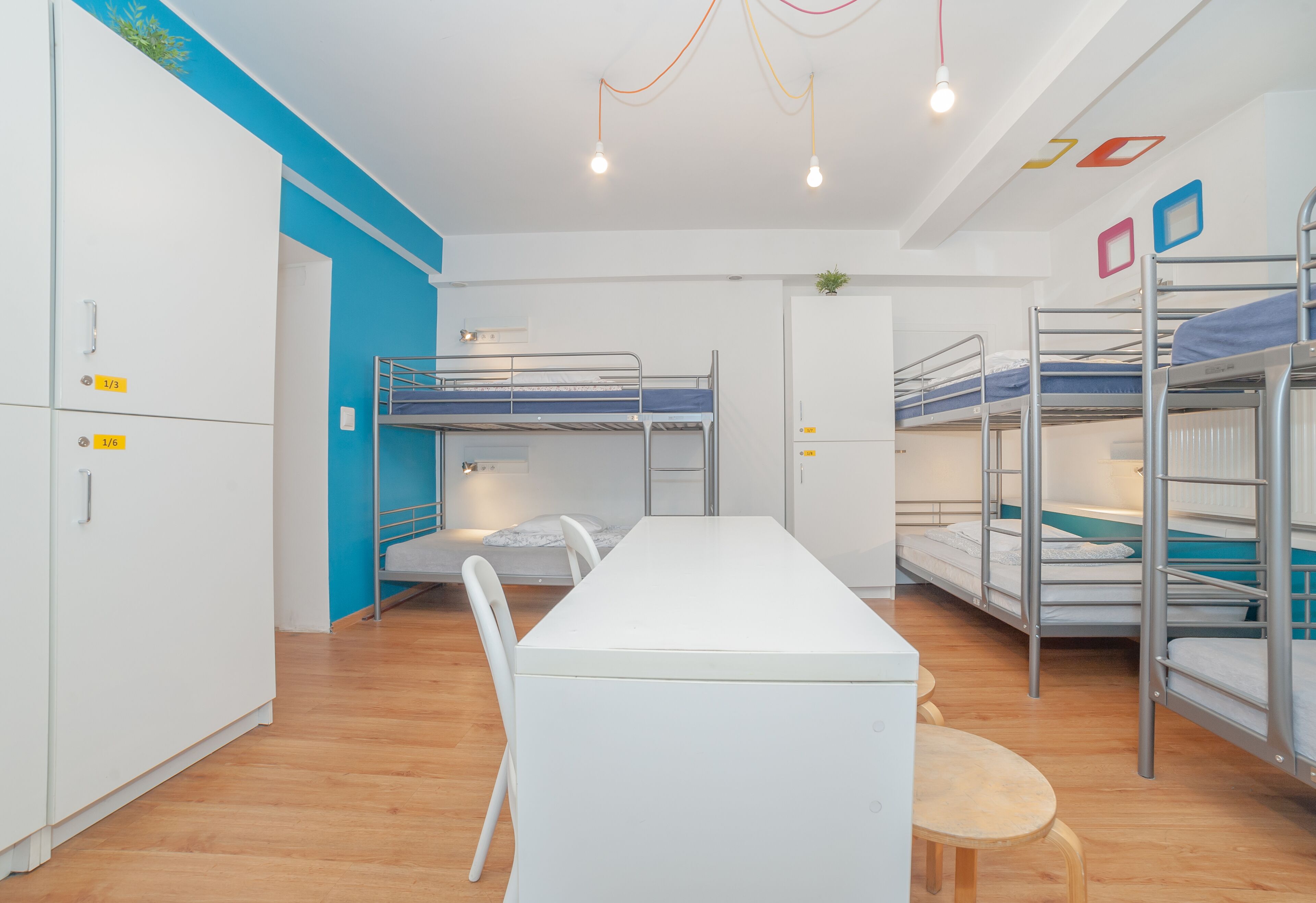 A dormitory room with bunk beds, a white desk, and a chair.