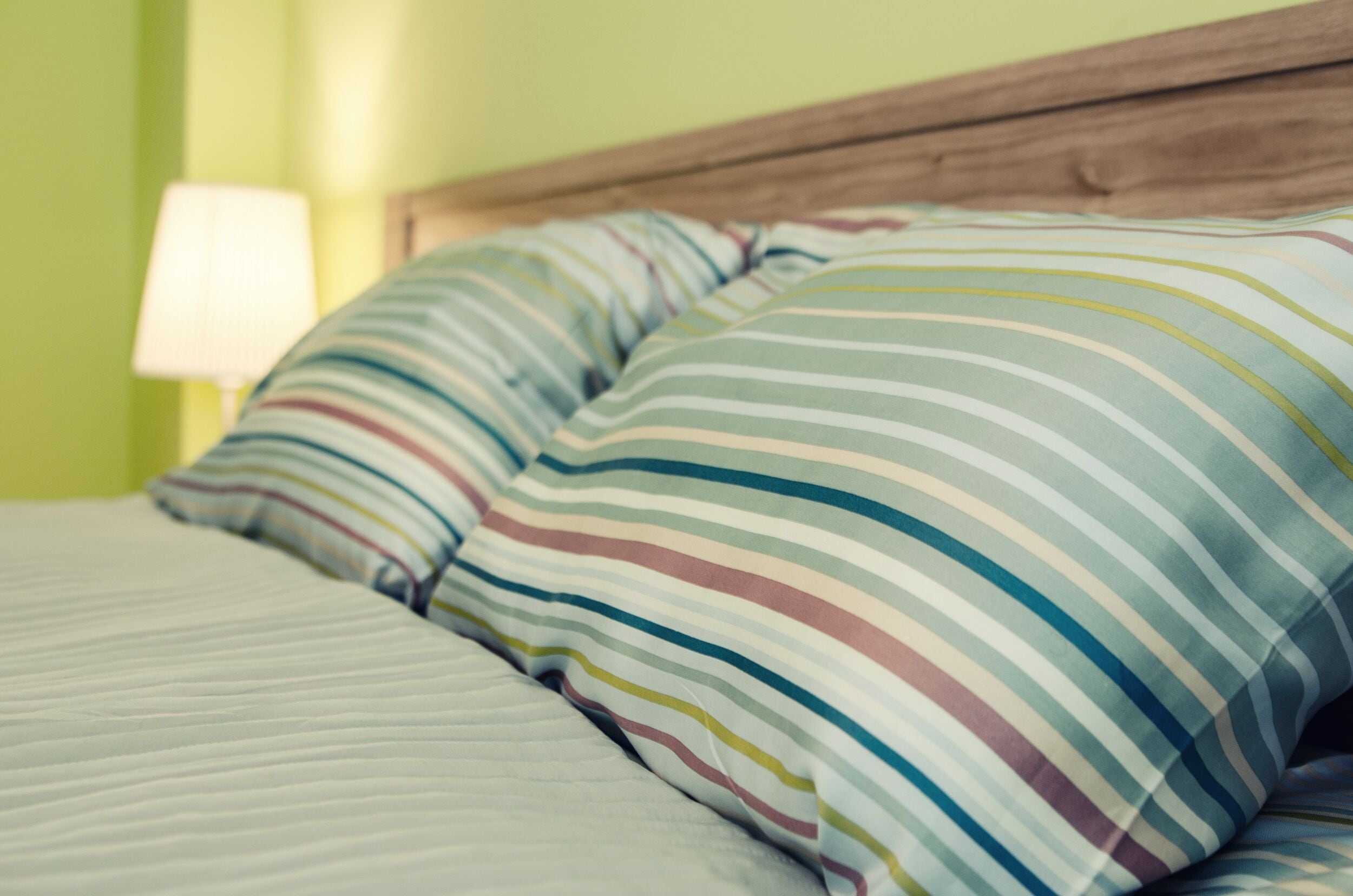 A bed with striped pillows and a wooden headboard.