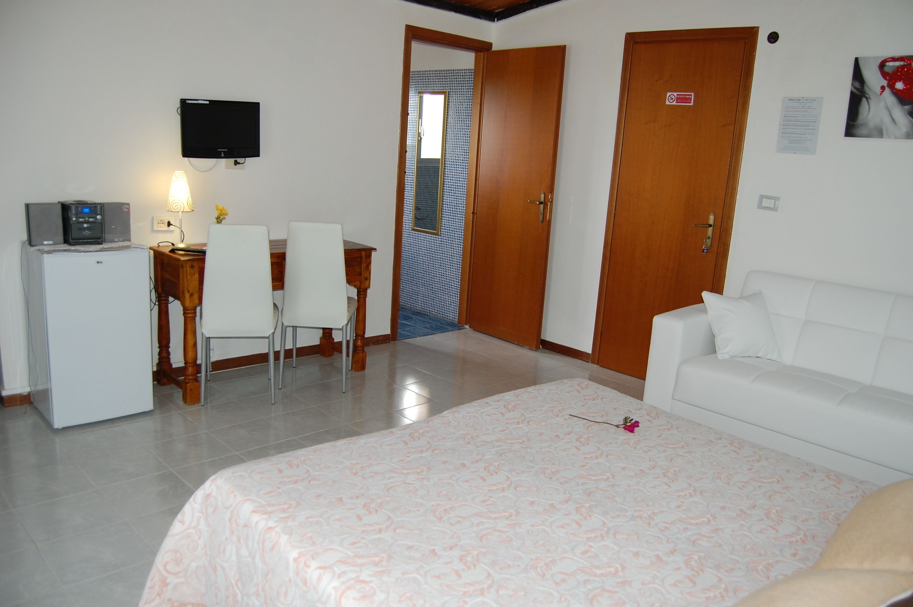 A hotel room with a bed, a desk with a computer, a TV, and a small refrigerator.