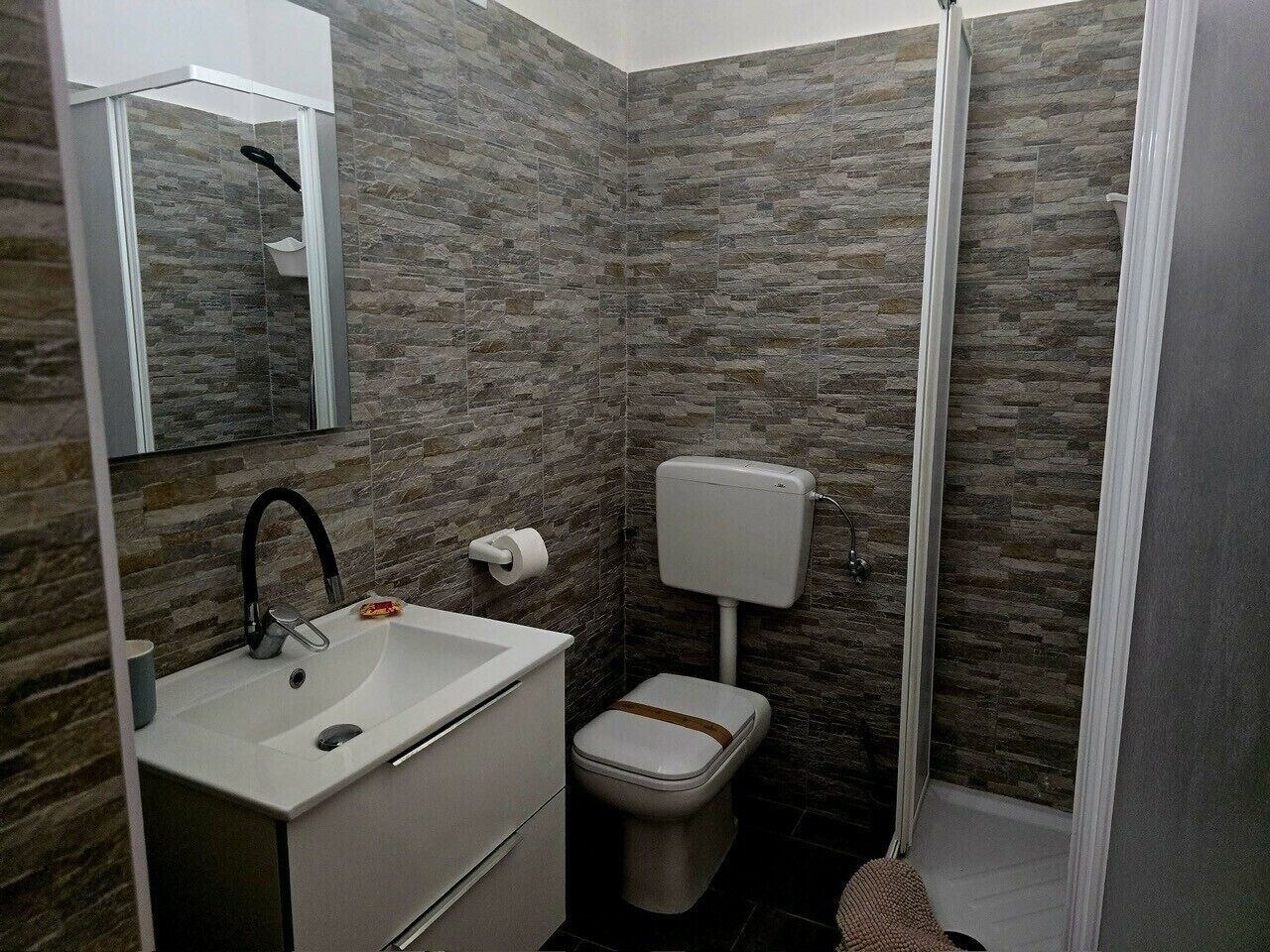 Baño con lavamanos blanco, inodoro y cabina de ducha.