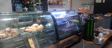A bakery display case with pastries and a coffee machine.