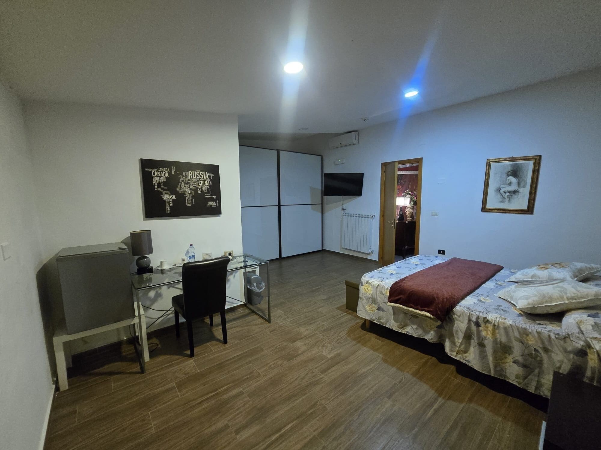 Une chambre à coucher comprenant un lit, un bureau, une chaise, une armoire et un téléviseur fixé au mur.