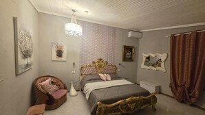 A bedroom with a bed, a chair, a small table, and a mirror on the wall. - Il Mirto e la Rosa Hoteles (Syracuse)