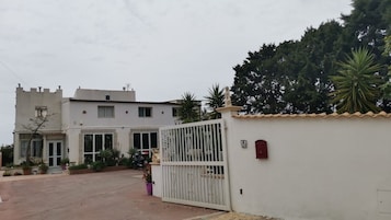 A gated residential property with a white exterior, a tower-like structure, and a gated entrance.