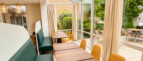 Un restaurante con mesas dentro, amplios ventanales y vistas al exterior.